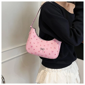 Detailed view of pink floral crescent bag with a silver metal bow charm on the strap