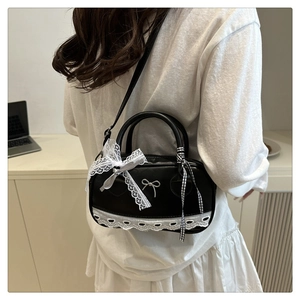 Close-up of black lace boston bag with silver bow buckle and checkered ribbon detail