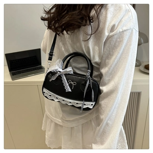 Detail of black faux leather Boston bag with lace trim and silver bow metallic accent