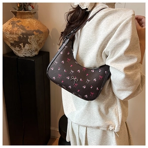 Detail of vintage brown shoulder bag with floral print and bow accents on faux leather