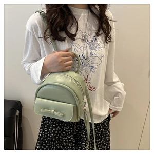 Close-up of a mint green mini backpack with a bow detail, shown as a crossbody bag
