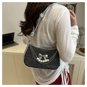 Detail of black glitter crossbody bag with silver bow and faux pearl chain strap