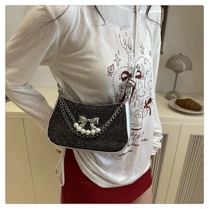 Detail of black glitter shoulder bag with silver bow charm and pearl accents