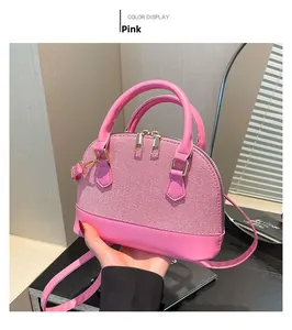 Pink mini shell bag with woven texture detail and detachable strap held in hand