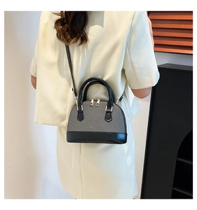 Detail view of a two-tone shell-shaped bag featuring woven texture and black leather straps