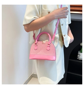 Macro detail of pink shell bag with woven texture, leather handles and gold hardware
