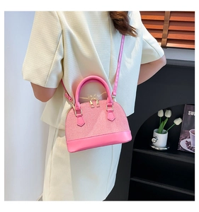 Pink shell bag with water ripple texture and gold hardware on model shoulder