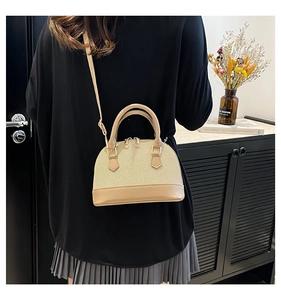 Detail of beige woven shell bag with leather trim and gold metal zipper hardware