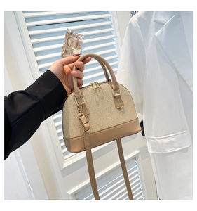 Detail of woven and leather shell bag with gold zippers and adjustable shoulder strap