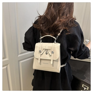 Close-up of cream PU leather mini backpack with bow detail and heart metal pendant