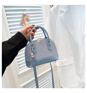 Detail of light blue shell bag featuring woven texture and adjustable shoulder strap