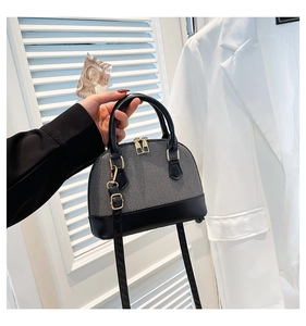 Detail of grey fabric and black leather shell bag with adjustable shoulder strap and gold zipper
