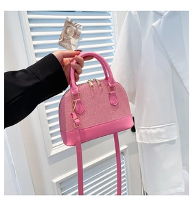 Detail of pink dome bag featuring woven texture, smooth leather and golden hardware