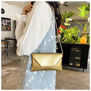 Detailansicht der goldenen Metallic-Umschlagtasche mit Faltenstruktur und Kette