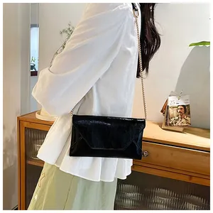 Modische schwarze Umschlagtasche mit goldener Kette am Model im Alltagsszenario