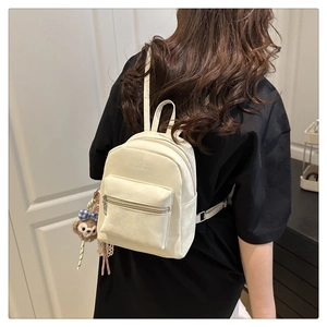 Detailansicht beige Mini-Rucksack mit Artumi-Logo und süßem Teddybär-Anhänger