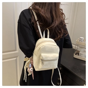 Rückansicht eines Models mit beigem Mini-Rucksack mit Bärenanhänger und Quasten-Details