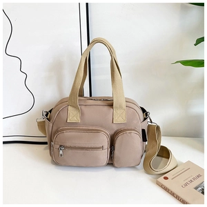 Detail of khaki nylon pillow bag featuring double front zip pockets and wide woven handles