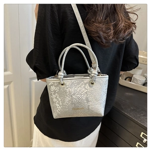 Detail of silver snake-pattern bucket bag with FASHION text and metal grommet strap