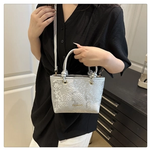 Detail of silver snake-patterned handbag featuring braided handle and fashion logo