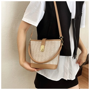 Detail of handwoven beige bucket bag with brown leather trim and golden metal clasp