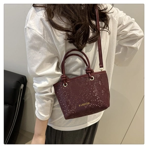 Détail du sac seau bordeaux en similicuir motif serpent avec logo doré et bandoulière