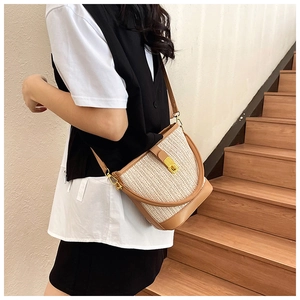 Detail view of woven straw bucket bag with brown faux leather trim and gold twist lock