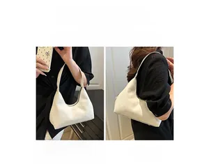 Detail view of cream half-moon handbag showing shoulder and handheld carrying options
