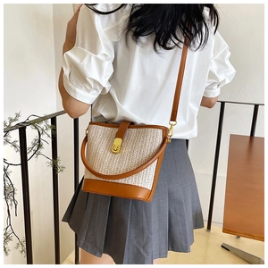 Model showing a woven bucket bag with leather trim and adjustable crossbody strap
