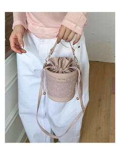 Detail of pink bucket bag with drawstring closure and dotted mesh overlay and gold hardware
