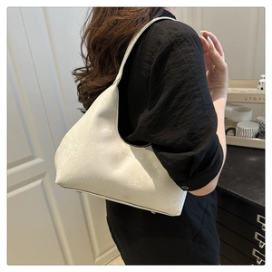 Detail of white faux snake leather hobo bag showing smooth crescent shape and silver studs