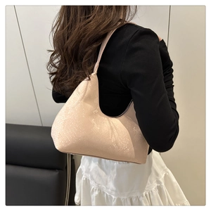 Détail d'un sac hobo en cuir rose texturé porté à l'épaule par un mannequin