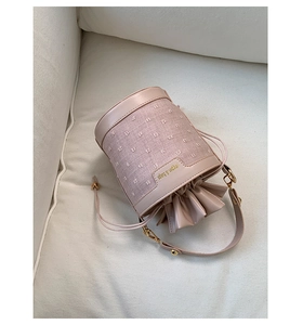 Detail of pink bucket bag featuring textured fabric and leather drawstring closure