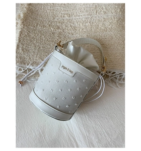 Close-up of white bucket bag featuring textured fabric and gold jingpin & bags metal logo