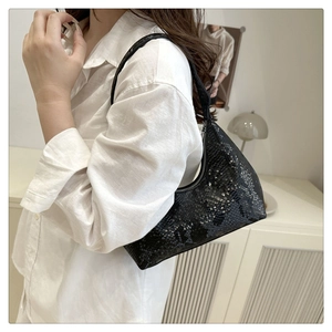 Detail of black snake pattern hobo bag worn on shoulder by model with metal zipper
