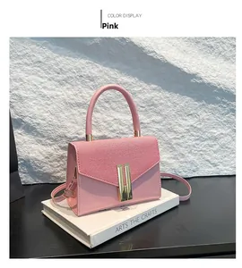 Pink PU leather crossbody bag with textured flap and gold buckle on a white book
