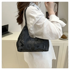Minimalist black tote bag with snake texture pattern worn by model in a modern setting