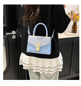Close-up of light blue crossbody bag with textured leather and gold buckle