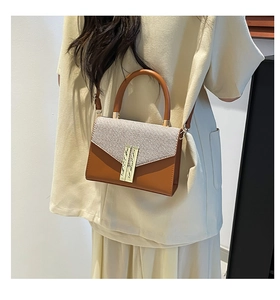 Detailed view of caramel leather and grey fabric crossbody bag with a gold bar lock