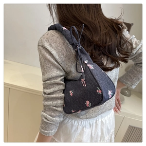 Detail of floral denim shoulder bag featuring pink roses and ribbon bow decorations