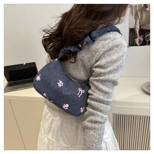Detail of blue denim crescent bag with pink floral rose print and ruffled shoulder strap