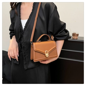 Detail view of the brown leather crossbody bag with a golden oval twist lock and slim strap
