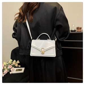 Elegant white crossbody bag with gold metal buckle shown in a stylish urban setting