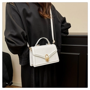 Detail of white leather crossbody bag featuring gold metal oval buckle and smooth texture