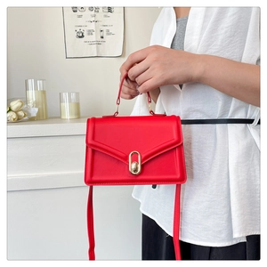 Detail of red mini crossbody bag with golden oval twist lock and smooth leather texture
