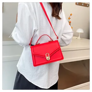 Detailed view of the red leather shoulder bag with gold metal oval twist lock closure