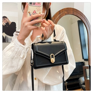 Detailed view of black textured leather envelope bag with gold oval clasp and handle