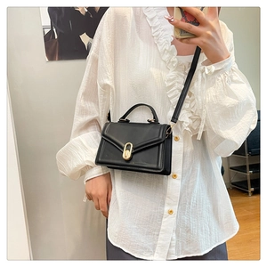 Detail of black crossbody bag featuring a golden twist lock and sleek PU leather finish