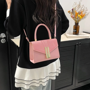 Pink faux leather crossbody bag featuring woven texture and gold metal buckle details