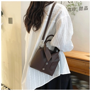 Detail of dark brown lychee leather handbag with shirt-style collar design and silver buttons
